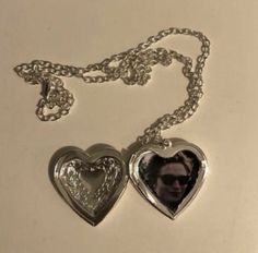 two silver heart shaped lockes with a man's face in the center on a chain