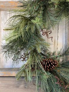 a pine cone is hanging from the branch of a christmas wreath on a wooden door