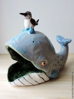 a ceramic figurine of a bird sitting on top of a humpback whale