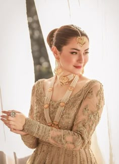 a woman wearing a dress and jewelry standing in front of a window