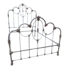 a metal bed frame with ornate designs on the headboard and foot board, against a white background