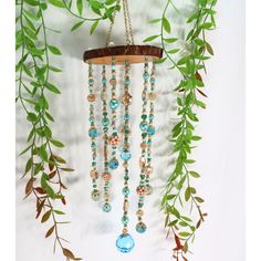 a wind chime hanging from a tree branch with beads and leaves on it's side