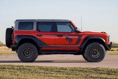 a red jeep parked on top of a grass covered field