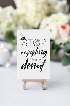 a sign sitting on top of a table next to a vase filled with white flowers