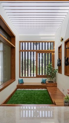 a living room filled with lots of windows next to a green rug and potted plants