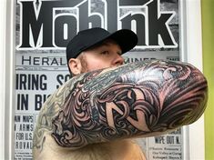 a man with a large tattoo on his arm and shoulder is looking at the camera