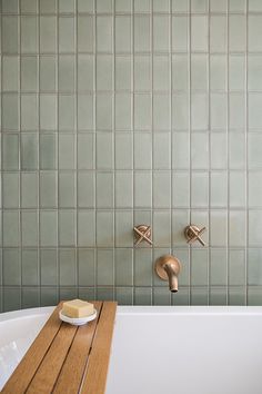 a bathtub with two soap bars on the side and a wooden tray in front of it