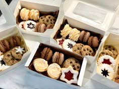 four boxes filled with assorted cookies and pastries on top of a white table