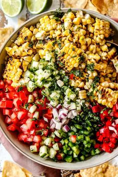 a bowl filled with corn, tomatoes, onions and cilantro on top of tortilla chips