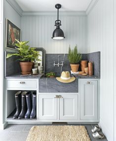 a kitchen with white cabinets and gray counter tops, potted plants on the wall