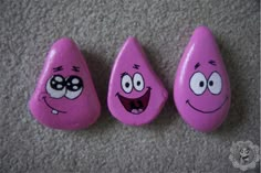 three pink rocks with faces painted on them sitting on the floor next to each other