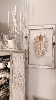 an old white cabinet is next to a candle holder and other items on the table