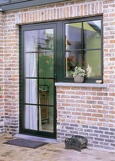 a brick building with an open window and potted plants in the window sill