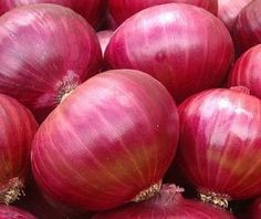 a pile of red onions sitting on top of green grass