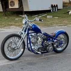 a blue motorcycle is parked on the side of the road in front of a trailer