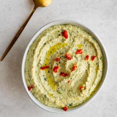 a white bowl filled with hummus next to a spoon