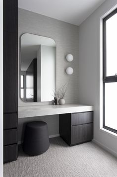 a bathroom with a vanity, mirror and stool next to a window in the room