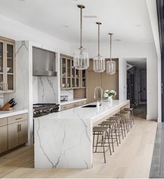 a large kitchen with marble counter tops and wooden flooring, along with bar stools