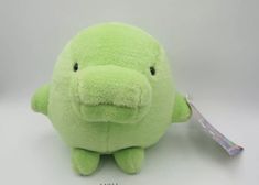 a green stuffed animal with a toothbrush in it's mouth on a white surface