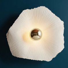 an overhead view of a white flower shaped light fixture on a blue wall with a circular mirror in the center