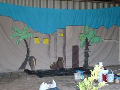 an outdoor stage set up with palm trees and other items on the ground in front of it