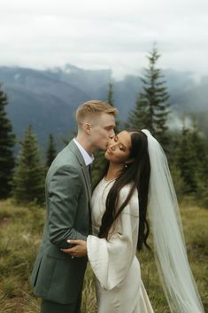 a bride and groom kissing in the mountains