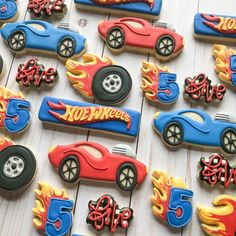 decorated cookies with hot wheels and cars are displayed on a white wooden surface, ready to be eaten