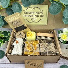 a box filled with soap, scrubs and other items next to some green leaves