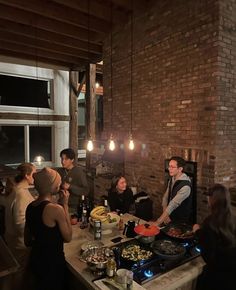 a group of people standing around a table with food and drinks on it in a room