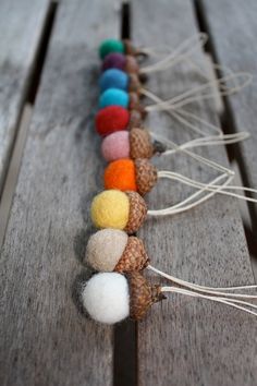 a row of pine cones sitting on top of a wooden table covered in pom - poms