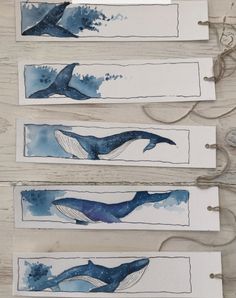 three watercolor paintings of blue whale tails on white paper with twine cords attached to them