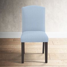 a blue and white striped chair sitting on top of a hard wood floor next to a wall