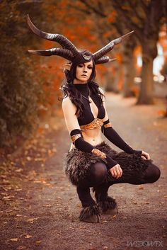 a woman with horns is sitting on the ground