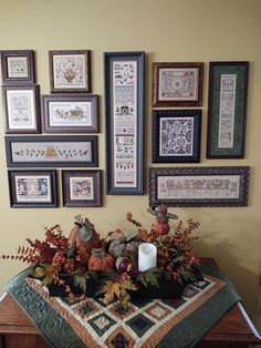 a table topped with lots of framed pictures next to a vase filled with flowers and leaves