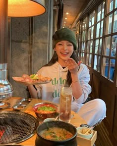 a woman sitting at a table with food in front of her and holding a plate