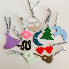 a collection of christmas ornament hanging from strings on a white table with a disco ball in the background