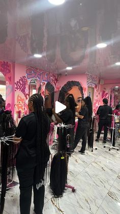 a group of women standing in front of a pink wall with lots of mirrors on it