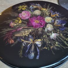 a black plate with flowers painted on it