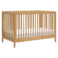 a wooden crib with white sheets on the bottom and side rails, against a white background