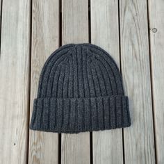 a gray knitted beanie sitting on top of a wooden floor