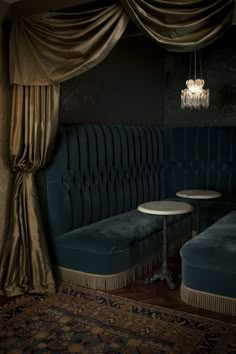 a blue couch sitting under a window next to a table with a chandelier