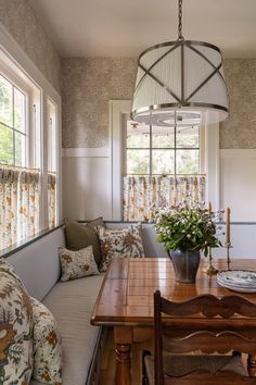 a wooden table sitting under a large window next to a couch and chair in a living room