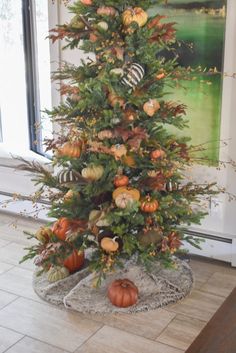 a decorated christmas tree with pumpkins and greenery