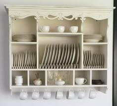 a white china cabinet filled with dishes and cups