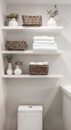 a white toilet sitting in a bathroom next to shelves filled with towels and other items