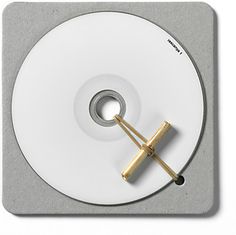 a white disc with a gold handle is on top of a gray and grey coaster