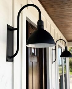 an outdoor wall light on the side of a house with white siding and wood ceiling