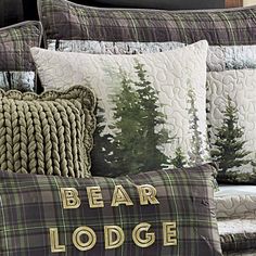 a bed covered in pillows and blankets with bear lodge on the pillow case next to it