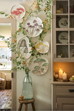 plates are hanging on the wall with flowers in vases next to them and candles