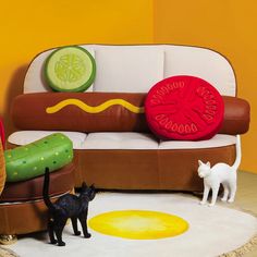 two cats are standing in front of a couch with hotdogs and hamburger rings on it